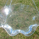 A clear acrylic bird bath filled with water hanging over a green lawn.